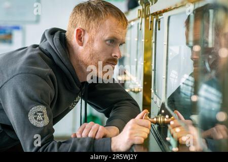 Still Man controlla i livelli di alcool nella Spirit Safe presso la Distilleria Ardbeg, Isle of Islay, Inner Hebrides, Scozia, Regno Unito Foto Stock