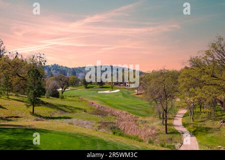 Una vista aerea di un lussureggiante campo da golf, caratterizzato da green e fairway circondati da alberi e arbusti Foto Stock