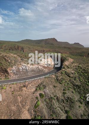 Una strada tortuosa di montagna serpeggia nel deserto, crogiolandosi nella luce soffusa di una giornata nuvolosa Foto Stock