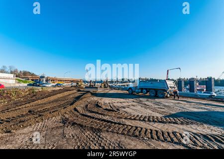 Un autocarro, una gru, un bulldozer e due pale a motore su un cantiere di costruzione di terra coperto da cingoli per la costruzione di rampe autostradali. Foto Stock