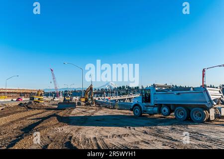 Un autocarro, una gru, un bulldozer e due pale a motore su un cantiere di costruzione di terra coperto da cingoli per la costruzione di rampe autostradali. Foto Stock