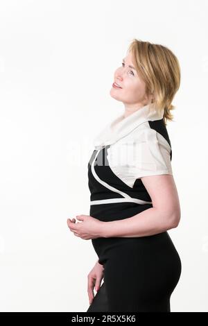 Donna bionda di mezza età ispirata che guarda in alto, pensando a nuove idee creative. Elegante donna d'affari europea di 49 anni sorridente con capelli corti. Posi Foto Stock