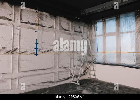 Finestre e parete ricoperte di pellicola di plastica in camera vuota Foto Stock