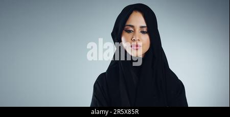 Le ceneri hanno ottenuto l'Islam nel suo cuore. Studio di una giovane donna d'affari musulmana su sfondo grigio. Foto Stock