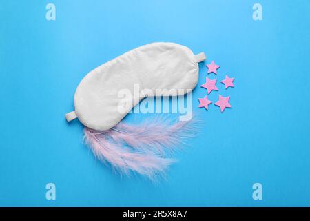 Maschera morbida, stelle decorative e piume rosa su sfondo azzurro, giacitura piatta Foto Stock