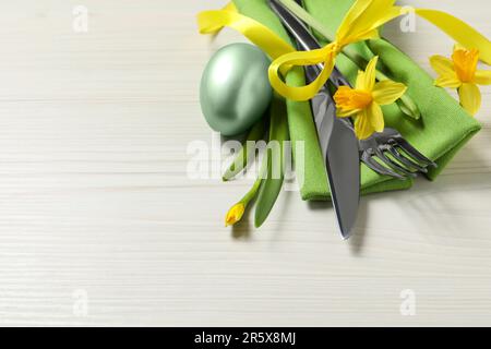 Set di posate, uovo dipinto e bellissimi fiori su tavolo di legno, spazio per il testo. Festa di Pasqua Foto Stock