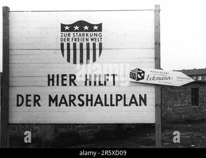 Un cartello nella regione della Ruhr in Germania che pubblicizza il presnece del piano Marshall in ricostruzione. Il piano Marshall era un programma di aiuti finanziari molto ambizioso proposto dal Segretario di Stato americano George Marshall. Capì che un'Europa distrutta e prostrata doveva avere un aiuto finanziario se dovesse riprendersi e rimuovere la minaccia dell'insurrezione comunista. L'aiuto non è stato concesso in prestito e ogni paese ha deciso come utilizzare i fondi. Nei tre anni del programma gli Stati Uniti hanno dato all’Europa $13 miliardi di dollari, una somma colossale del valore di $175 miliardi di dollari ai valori di oggi. Questo piano lungimirante e generoso era un Foto Stock