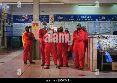 Team professionale di pulitori di pesce con uniforme rossa sul mercato del pesce al Mina. Ritratto di gruppo del personale del mercato del pesce. Foto Stock