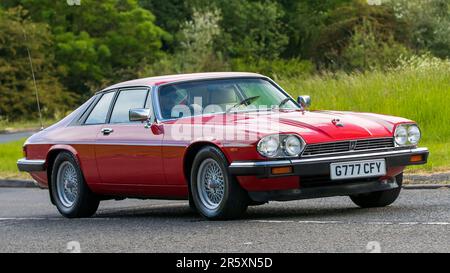 Stony Stratford, Regno Unito - 4th 2023 giugno: 1989 auto rossa JAGUAR XJS Classic che viaggia su una strada di campagna inglese. Foto Stock