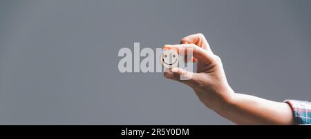 Esperienza del cliente con il concetto di servizio e soddisfazione del cliente. Donna mano che tiene emoticon faccia eccellente valutazione su cubo di legno, Banner con copia Foto Stock