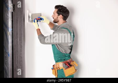 Elettricista che installa la scatola dei fusibili con un cacciavite in interni Foto Stock