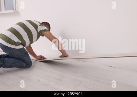 Lavoratore professionista che installa la nuova pavimentazione laminata all'interno Foto Stock