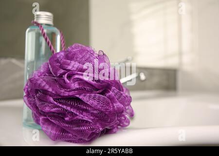 Soffio doccia viola e bottiglia di gel per il lavaggio del corpo sul lavandino in bagno, guardaroba. Spazio per il testo Foto Stock