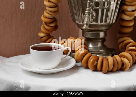 Samovar vintage, tazza di bevanda calda e bagel secchi serviti sul tavolo. Tradizionale cerimonia del tè russo Foto Stock