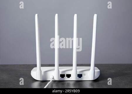Router Wi-Fi su tavolo grigio con texture, vista posteriore Foto Stock