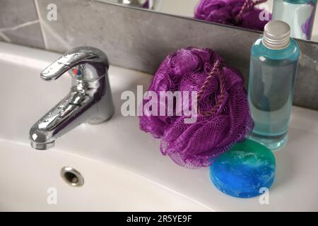 Soffione doccia viola e prodotti cosmetici sul lavandino in bagno Foto Stock