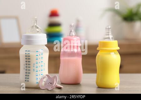 Biberon con formula per bambini e succhietto su un tavolo di legno all'interno Foto Stock