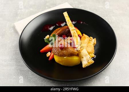 Piatto con delizioso pollo, pastinaca e fragole sul tavolo grigio. Stilista alimentare Foto Stock