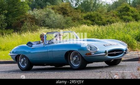 Stony Stratford, Regno Unito - Giugno 4th 2023: 1967 AUTO classica JAGUAR e-TYPE BLU che viaggia su una strada di campagna inglese. Foto Stock