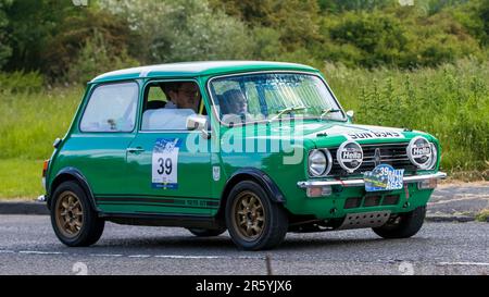 Stony Stratford, Regno Unito - Giugno 4th 2023: 1977 mini 1275 GT auto classica verde in viaggio su una strada di campagna inglese. Foto Stock