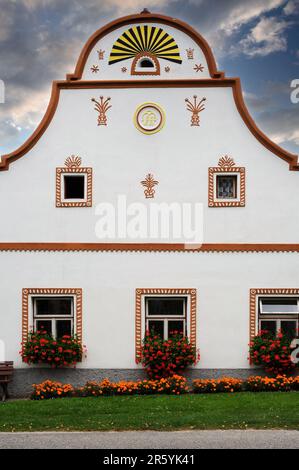 La decorazione in stucco sulla facciata della casa indica la professione di agricoltore del proprietario, oltre a indicare la data di costruzione della casa, 1852, e le iniziali del proprietario. A Holašovice, Boemia meridionale, Repubblica Ceca o Repubblica Ceca, un esempio ben conservato di un tradizionale villaggio dell'Europa centrale con molte case contadine ricostruite nel 1800s d.C. in uno stile noto come barocco popolare della Boemia meridionale, barocco rurale o barocco rustico. Foto Stock