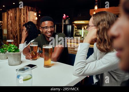 Felice giovane gruppo multirazziale di amici in abbigliamento casual sorridendo e parlando durante la celebrazione Foto Stock