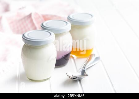Yogurt bianco e fruttato in vaso sul tavolo bianco. Foto Stock