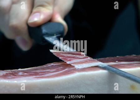 chef che taglia una fetta di prosciutto, di ottima qualità, con il coltello Foto Stock