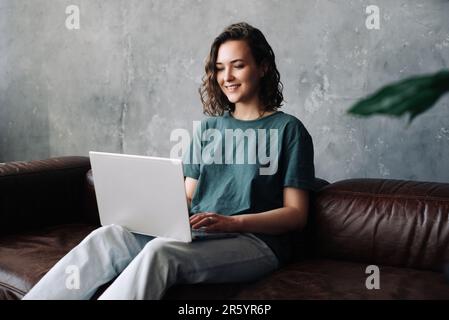 Produttività e indipendenza: La giovane donna si impegna nel lavoro e nello studio a distanza, utilizzando il notebook nel comfort di casa. Abbracciare i benefici di freela Foto Stock