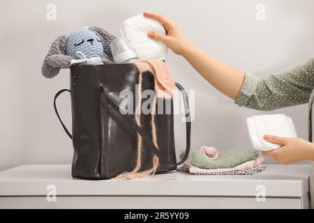 Donna che mette il pannolino nel sacchetto della madre al tavolo bianco all'interno, primo piano Foto Stock