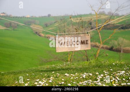 Carta di benvenuto. Asse di legno con parola appesa sulla corda in campagna Foto Stock