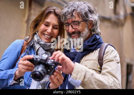 Primo piano sorridente coppia in pensione che guarda le foto della fotocamera. Pensionati maturi turisti. Foto Stock