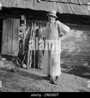 Maramures County, Romania, circa 1981. Uomo locale in un villaggio che indossa abiti tradizionali e 'opinci', una calzatura in pelle fatta a mano. Foto Stock