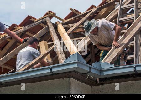 Un gruppo di maestri sta lavorando sul tetto di una casa privata per sostituire una vecchia piastrella Foto Stock