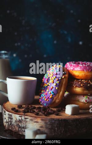 Pila di ciambelle assortite e una tazza di caffè su uno sfondo spazio. Foto Stock