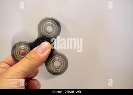 Fidget Spinner che ruota nella mano dell'uomo con vista ravvicinata di sfocatura del movimento Foto Stock