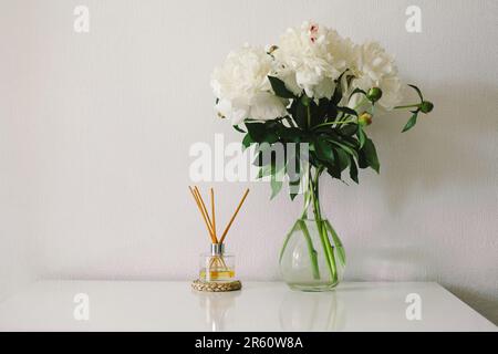 Bastoncini di incenso e vaso con peonie bianche. Fragranza ecologica per la casa Foto Stock