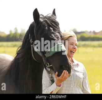 Una donna bionda che abbraccia un pony caduto nero Foto Stock