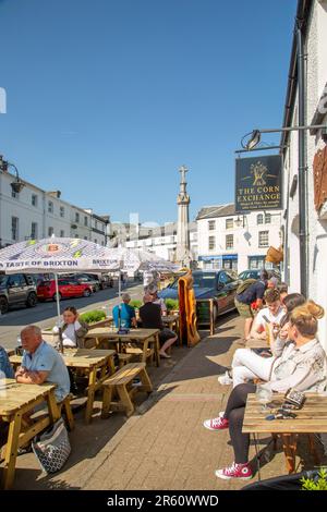 Persone che mangiano e bevono all'aperto ai tavoli sulla High Street, nella città del mercato gallese di Crickhowell Powys Foto Stock