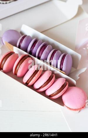 Macaron rosa e viola con ripieno di cioccolato in confezione regalo. L'idea di un regalo dolce carino per una ragazza per una festa Foto Stock