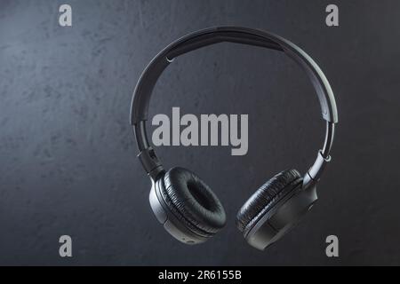 Grandi cuffie wireless su sfondo scuro. Cuffie nere, levitazione. Spazio di copia Foto Stock