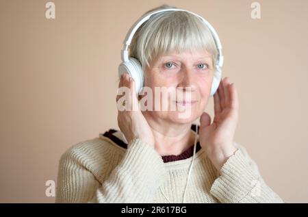 Bella donna di mezza età con cuffie a casa. Foto Stock