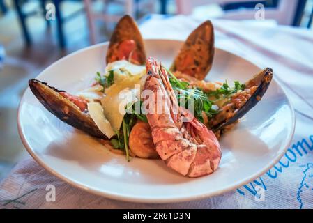 Classico risotto a base di pesce, con frutti di mare freschi e erbe aromatiche e spezie mediterranee. Cucina greca, taverna sfondo. Foto Stock