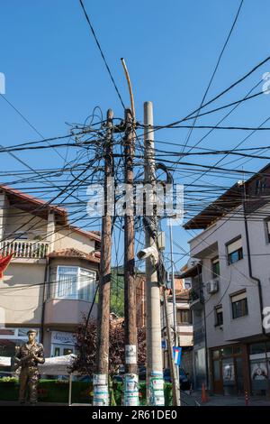Una massa aggrovigliata di cavi elettrici e cavi di alimentazione attaccati a un palo d'angolo della strada si è saltata l'una sull'altra a Prizren, Kosovo, ex Jugoslavia Foto Stock