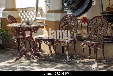 Sedie decorative con un tavolo nel cortile del tempio buddista Wat Pho Thong, Bangkok, Thailandia Foto Stock