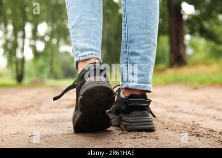 Sneaker da donna stilista con suola alta. Scarpa nera sportiva femminile su sfondo forestale. Calzature, scarpe casual in pelle. Modello, mock up Foto Stock