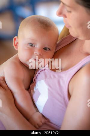 Una madre adorabile che cullava il suo bambino felice tra le braccia Foto Stock