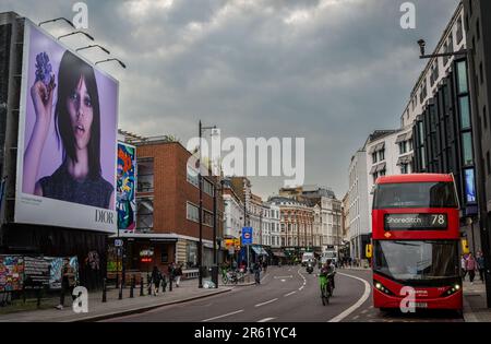 Londra, Regno Unito: Guardando verso nord lungo Shoreditch High Street a Londra. Con un autobus rosso di Londra e un cartellone pubblicitario. Foto Stock