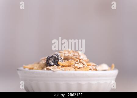 Un primo piano di farina d'avena secca in una ciotola di ceramica bianca su un tavolo Foto Stock