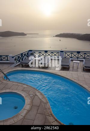 Lettini e piscine sulla terrazza nel villaggio di Imerovigli, con una splendida vista del tramonto sulla caldera di Santorini. Grecia Foto Stock